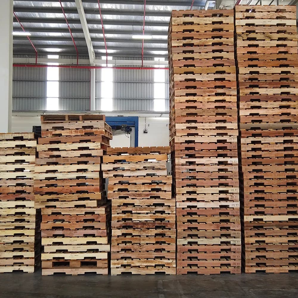 Tall stacks of 48 x 40 wood pallets inside a warehouse