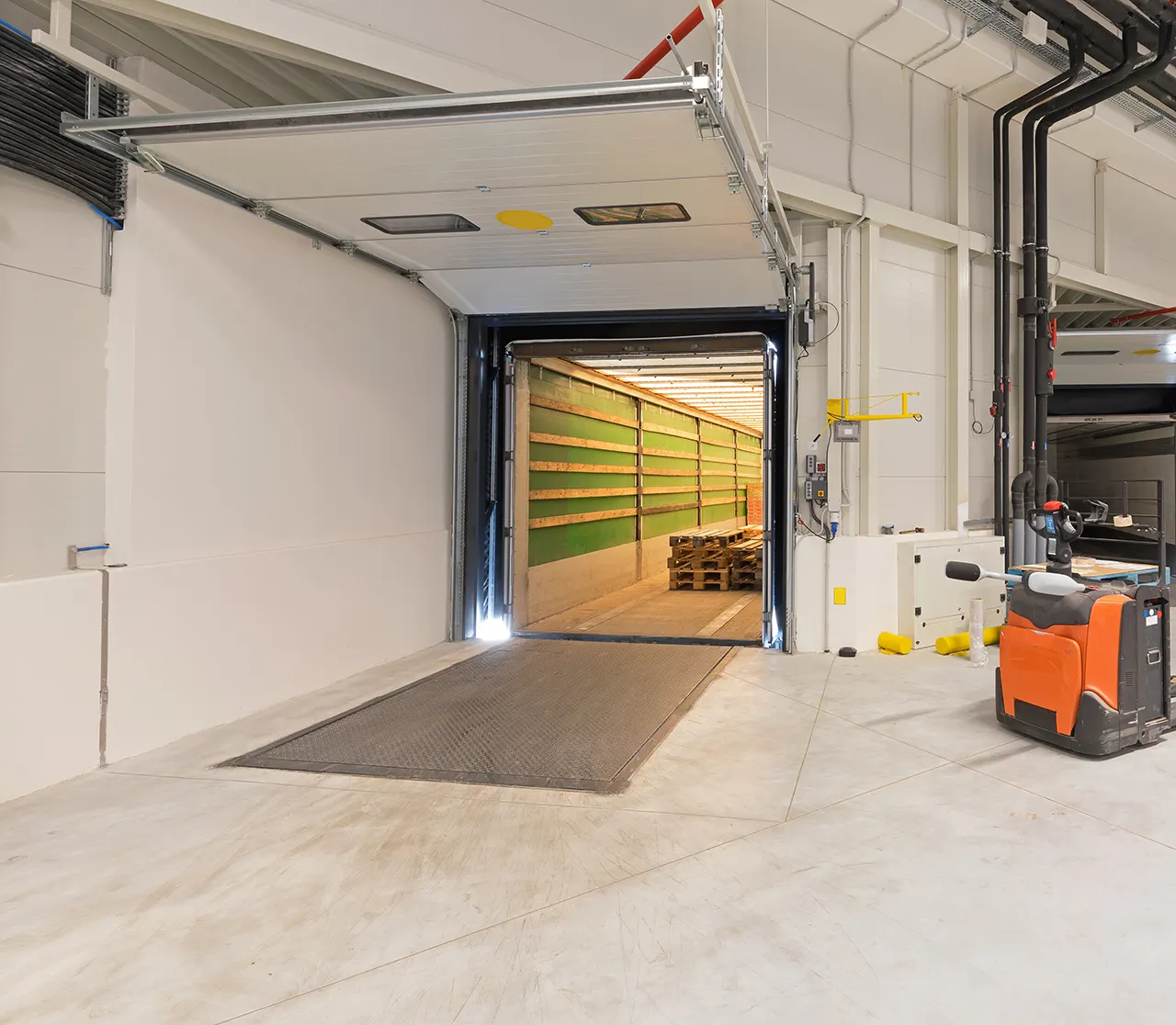 Open roller door at a warehouse dock with a lit trailer interior