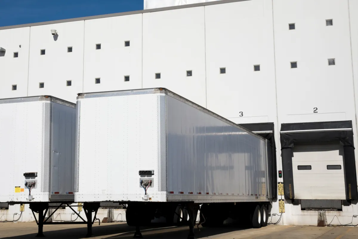 Large trailer parked at warehouse loading dock for pallet drop trailer service