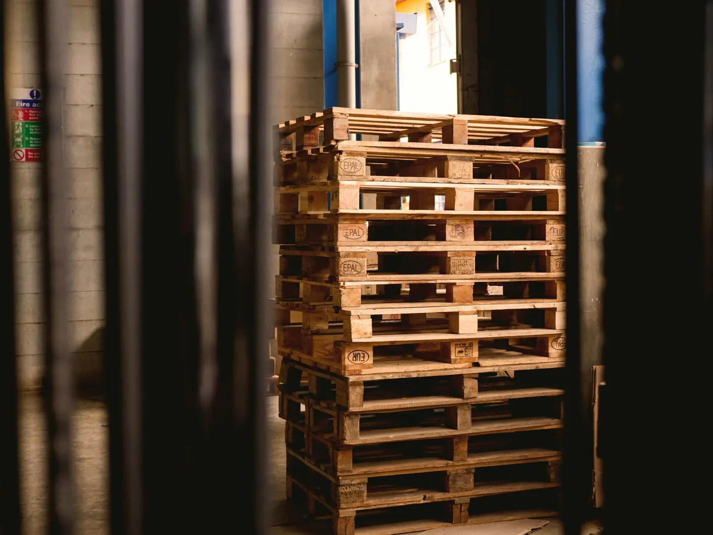 Stack of wood pallets seen between the mast bars of a forklift