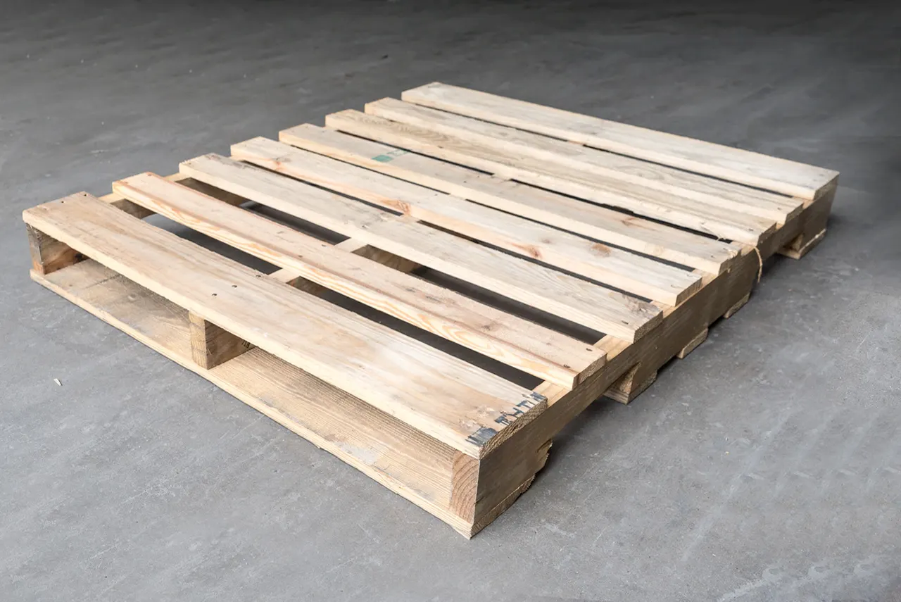 Clean light pine wood pallet on a grey concrete warehouse floor